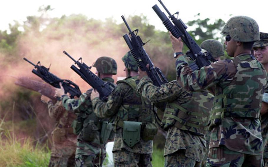 Members of the 31st Marine Expeditionary Unit aim for a distant hillside on Range 8 on Okinawa while firing practice rounds from the M203 grenade launchers attached to their M-16 A2s. The Marines on the far end are surrounded by a cloud of orange chalk that prematurely released from a practice round.