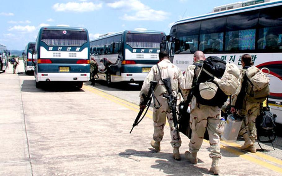 Under sunny skies at Osan Air Base, South Korea Monday, troops of Army's 2nd Infantry Divison head for buses that will take them to the flight line. Monday marked the start of a weeklong airlift of the division's 2nd Brigade Combat Team from Osan Air Base to Kuwait, for eventual duty in Iraq.