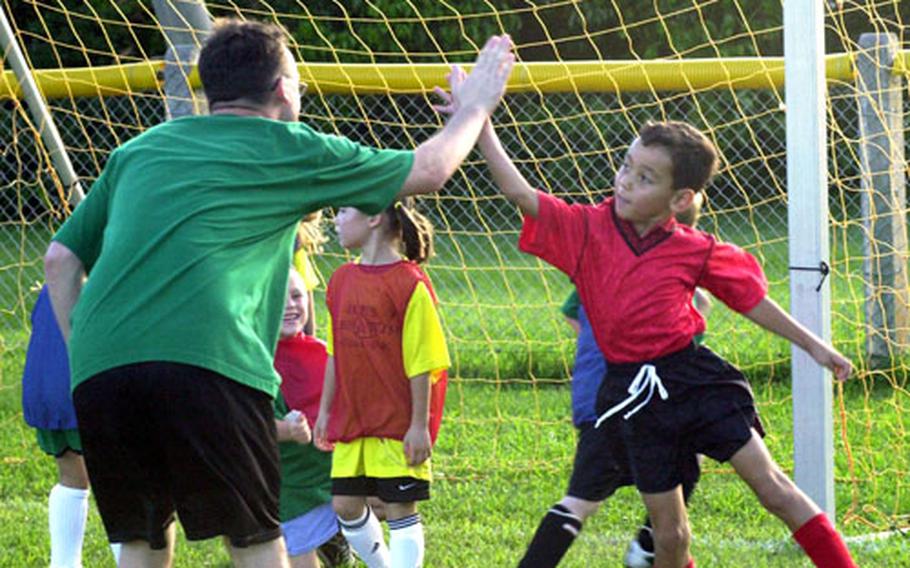 Austin LaRose, 6, give coach Zackary Leos a flying high five Friday at a soccer clinic on Kadena Air Base. More than 100 kids attended the weeklong soccer clinic that was held in honor of a little 7-month-old infant named Zoe who lost her life to meningitis last month.