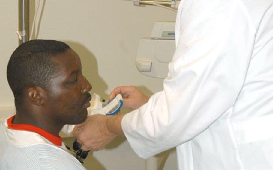 Col. Todd Hess, an ophthalmologist, removes the dressing on Spc. Xavier Pastchol's eye. Shrapnel from a roadside bomb attack in Iraq sliced open Pastchol's eye, damaged his jaw and left his arms pitted with wounds.