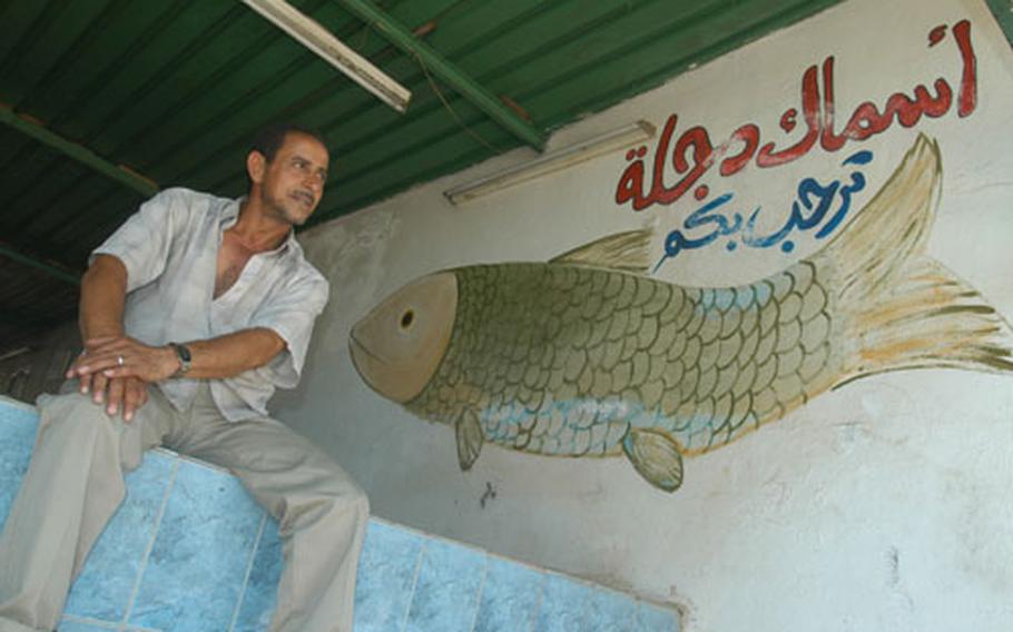 Muhan Hassan Mizaal al-Saadi sits in the doorway of his grilled fish restaurant Friday. Behind the restaurant, Army engineers are in the second phase of a project to renovate and re-open a large park on the east bank of the Tigris Restaurant in Baghdad's Rusafa neighborhood. Al-Saadi hopes that the park will bring people back to the park, and consequently, his restaurant.