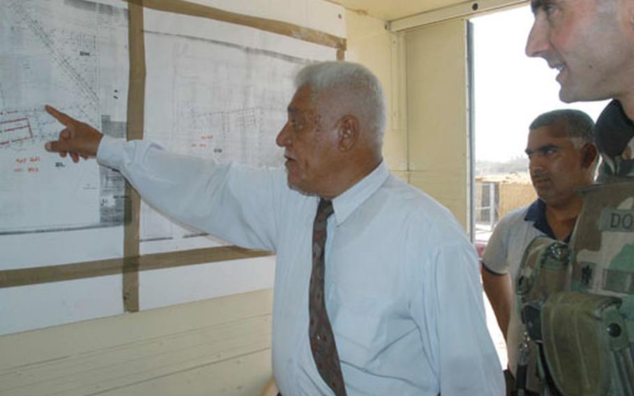 Lt. Col. Brian Dosa, commander of the 8th Engineer Battalion, looks on as construction manager Sheik Sabah al-Timimi points out the progress of sewer line construction in Baghdad's Zafraniya neighborhood.