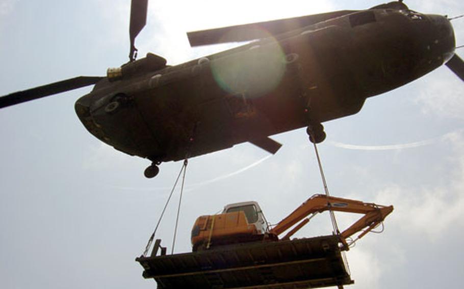 A CH-47 Chinook helicopter of Company A, 2nd Battalion, 52nd Aviation Regiment out of Camp Humphreys, South Korea, hauls a piece of construction equipment to a U.S. Army communications site atop a mountain near Kumi City on Monday. The Army's 36th Signal Battalion at Camp Walker in Taegu is demolishing old buildings at the site and plans to upgrade its radio equipment there.