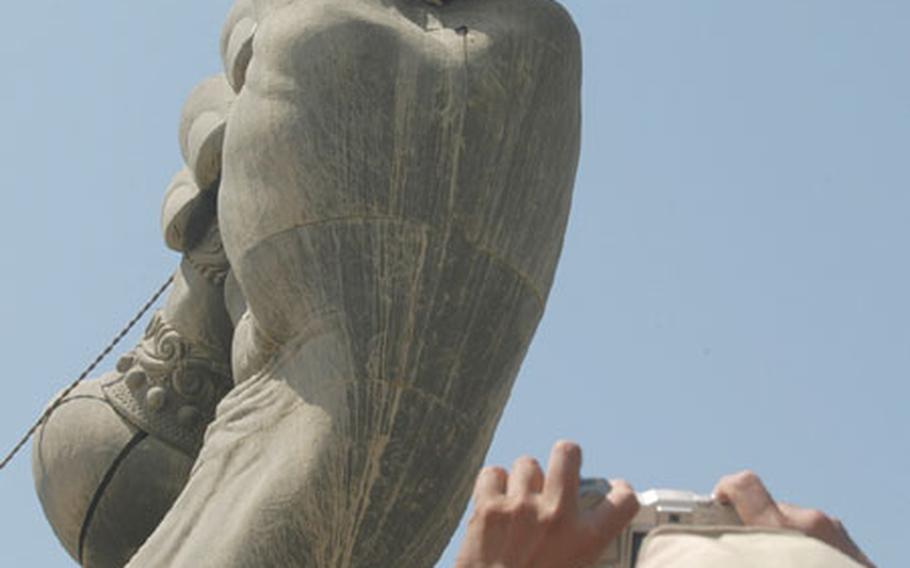 Petty Officer 1st Class Art Castillo takes a photograph of Petty Officer 2nd Class Curtis Sutherland, who leans out of the crossed-swords monument in Baghdad. The two, along with Petty Officer 1st Class Michael Miller and Petty Officer 3rd Class Oscar Reyesramos, spent a day in Bagdhad's International Zone, touring some of the area's top monuments.