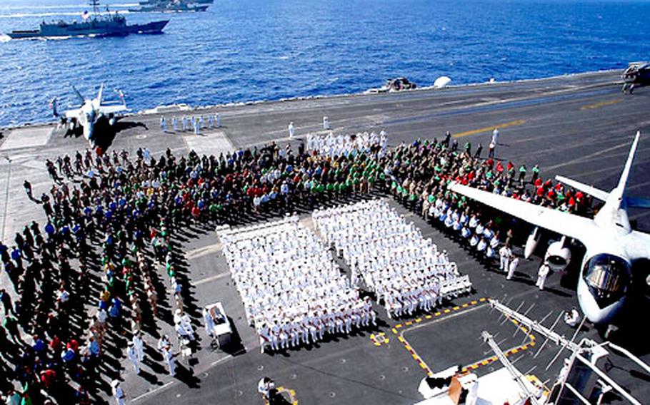 Sailors aboard USS John C. Stennis gather on the flight deck during a memorial service to honor four fallen sailors.