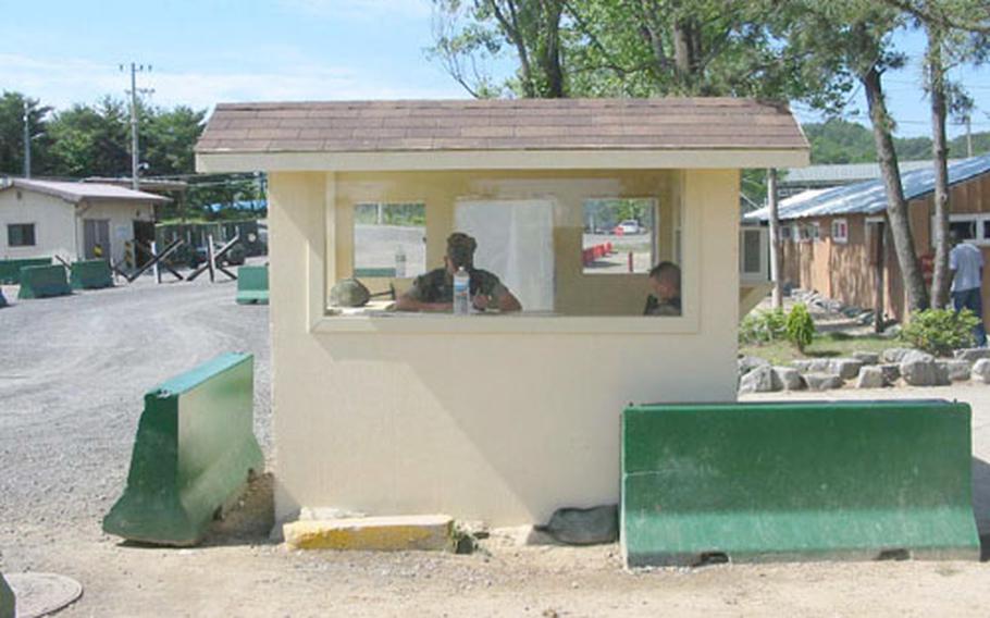 At Camp Mu Juk near Pohang, South Korea, a Marine pulls duty inside a security shack at the entrance to the spartan 84-acre logistics base. A modern gate security building with anti-terrorist devices will eventually replace the shack as part of a ten-year, $60 million plan to turn the base into a modern, full-status military installation.