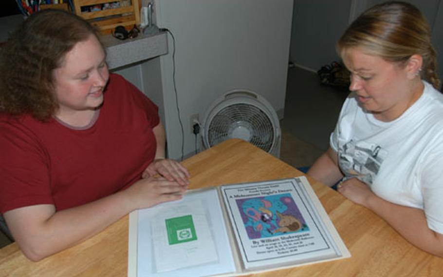 Misawa Theatre Guild members Sarah Schaal (left) and Amy Tjaden look at a guild flier advertising William Shakespeare's "A Mid Summer's Night Dream." The community theatre group at Misawa Air Base, Japan, is looking for new members after losing a core of active participants this summer. The next meeting is Sept. 19.