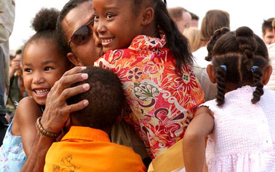 A senior airman returning home from deployment is greeted by his four children during a welcoming ceremony at Yokota Air Base.