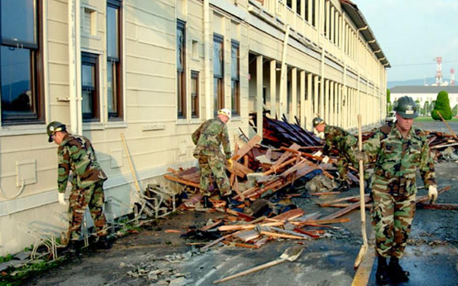 Servicemembers collect debris Wednesday following Typhoon Songda, which blew off about half of the roof at Iwakuni Marine Corps Air Station's Logistics Building the night before.