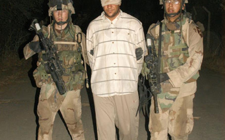 Soldiers from Company C, 1st Battalion, 506th Infantry Regiment march a detainee back to their forward operating base for further interrogation Saturday in Iraq.