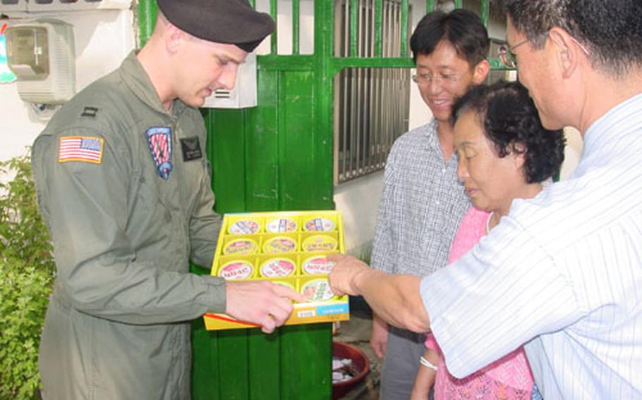 Capt. Matthew J. Bowman, commander of the Walker Army Heliport in Taegu, South Korea, explains the content of a Chusok gift set given to local residents living adjacent to the heliport Friday. The Army's Area IV Support Activity has given out gift sets to local residents for seven years. Chusok is one of Korea's major annual holidays and is similar to Thanksgiving in the United States.