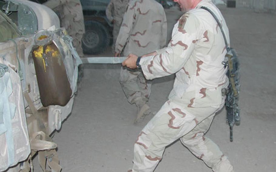 Sgt. First Class Brian Hester, from Mount Sterling, N.Y, Company B’s platoon sergeant also known as “Ammo Can” by his men, tightens a strap on an armored Humvee before a Wednesday night’s standard 12-hour mission.