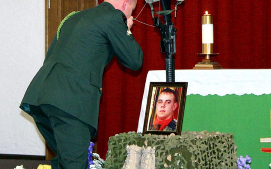 Spc. William Champion kisses the dog tags of Spc. Joshua Justice Henry as he says goodbye to his friend at a memorial service Tuesday in the base chapel at Schweinfurt, Germany.