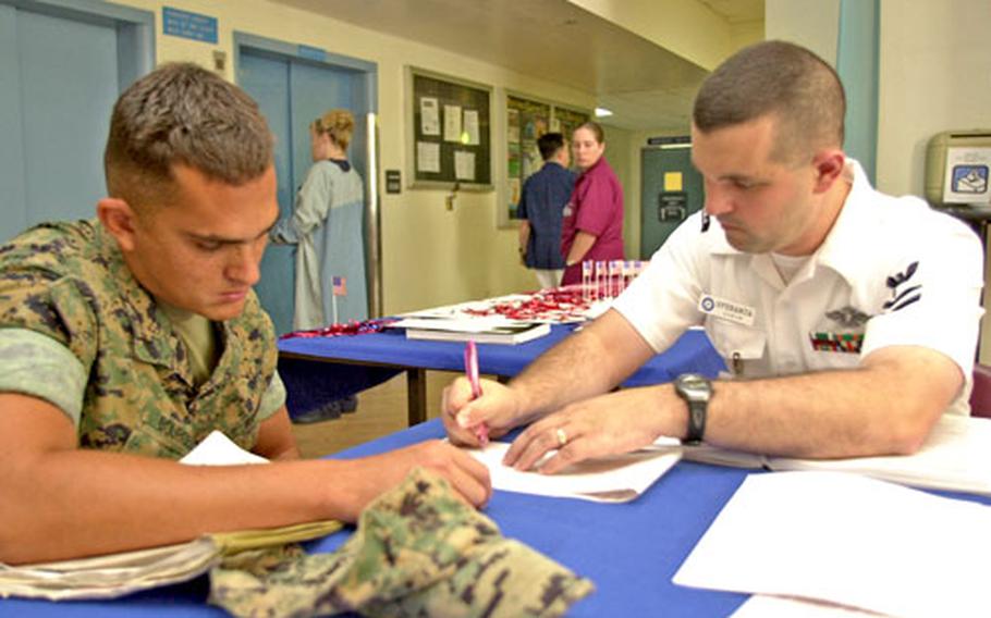 Petty Officer 1st Class Joe Speranza, right, a voting assistance volunteer, helps Lance Cpl. Steve Bourger with the paperwork during a voting drive Wednesday at U.S. Naval Hospital Okinawa.