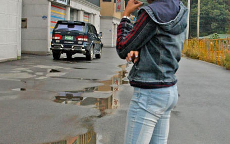 "Rain," a Filipina bar worker, stands outside some of the Toka-ri nightclubs that are suffering after the departure of 2nd Infantry Division soldiers who are deployed to Iraq. She says she ran away from her South Korean employers after they tried to force her to strip for club patrons.