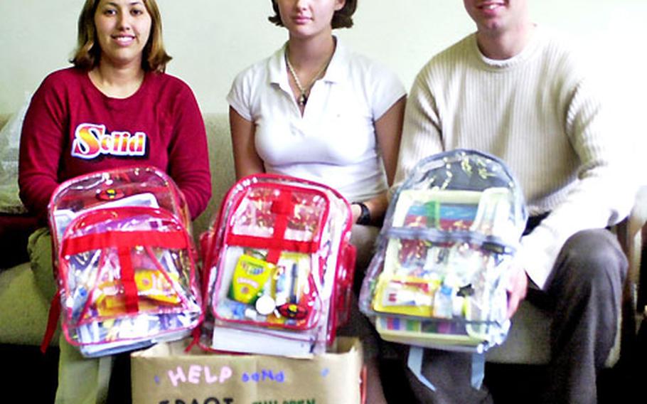 From left, Jessica Larson and Lance Cpls. Jenna Bennett and Spencer Watts hold school supplies they are sending to Marines in Iraq. Larson said the Marines use the items as "ice breakers" with children there.