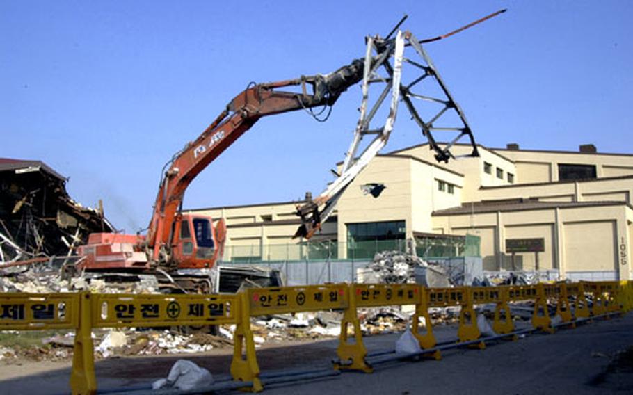 Workers tear down the old gym at Kunsan Air Base, South Korea, last Sunday. Replacing it is the newly built, state-of-the-art gym in the background.