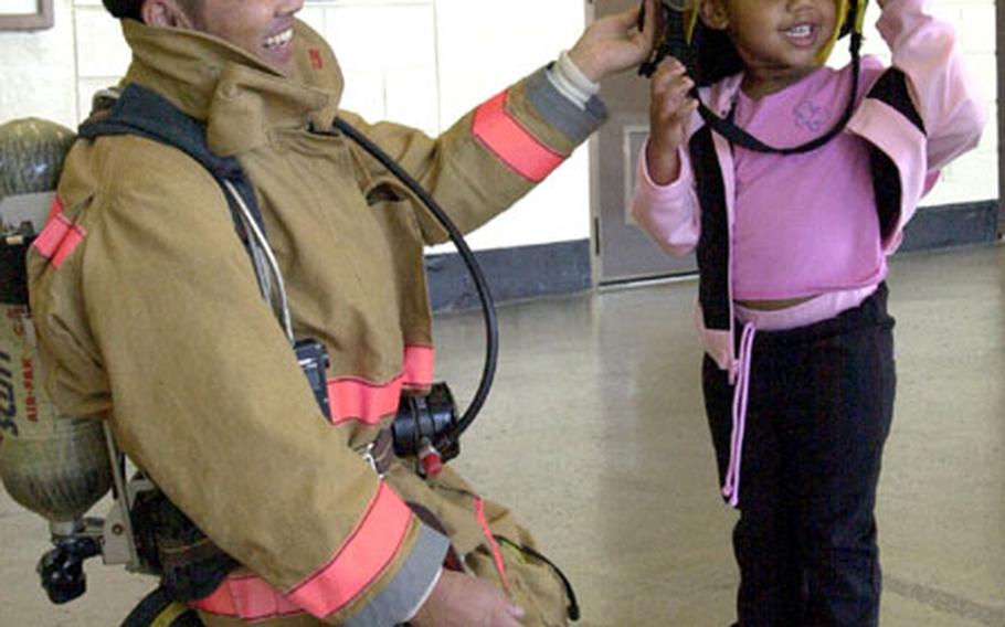 Gabrielle Parmer, 2, tries on the hat of a firefighter Friday during a visit to a Marine Corps fire station.