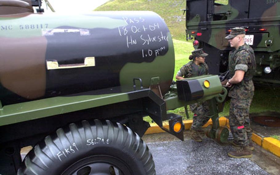 As Typhoon Tokage nears Okinawa, Pfcs. Lesli Espinoza, left, and Chris Blair, both from 3rd Tranportation Support Battalion, place a water bull in a barracks parking lot to prepare for the storm. Espinoza said the Marines begin to fill the water tanks when the base goes into Typhoon Condition 3.