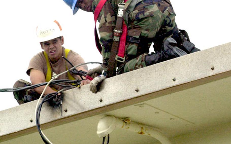 Airman 1st Class Arthur Trotta, left, and Airman Gregory Jenkins repair power lines to a house in Camp Foster's Futenma housing area Wednesday. The troops from Kadena Air Base's 18th Civil Engineer Squadron were fixing the lines after they were blown off the building during Typhoon Tokage Tuesday night.
