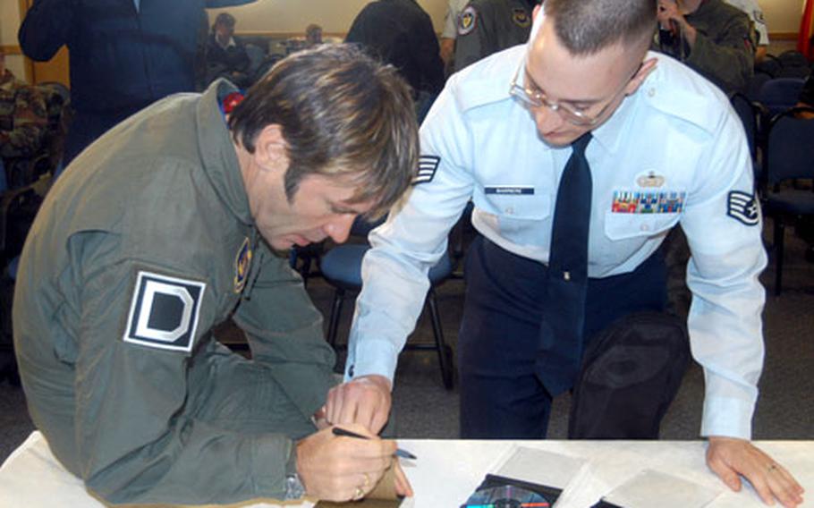 Bruce Dickinson, singer for Iron Maiden, signs an autograph for Staff Sgt. Thomas Barriere of the 100th Operational Support Squadron on Monday at RAF Mildenhall, England. Dickinson, who is a commercial pilot, flew a refueling mission later in the day on a KC-135 Stratotanker. He is filming a series on classic aircraft for the Discovery Channel.