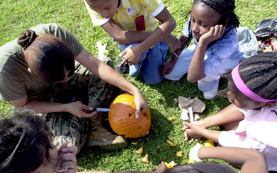 Marine Pfc. Joyce Funderburk, a volunteer with the Single Marine Program, carves the face of a pumpkin after the group of fourth graders drew it. More than 20 Marines volunteered their time to help 300 students at Kinser Elementary School carve pumpkins.