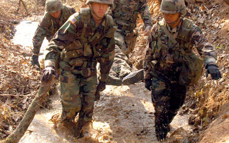Soldiers carry a "casualty" through a flooded trench Wednesday at Warrior Base.