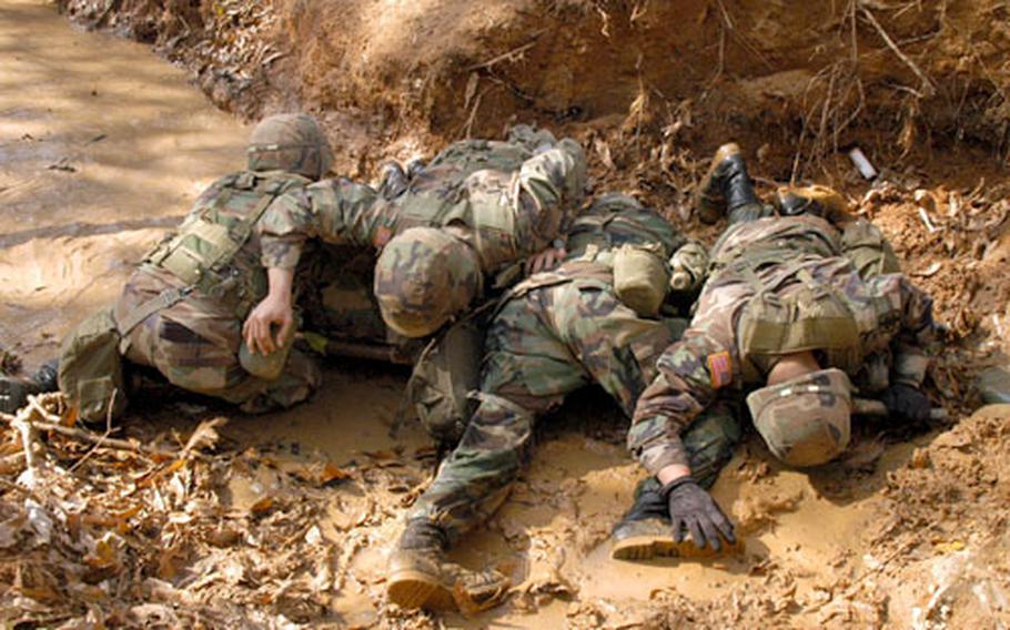 Soldiers shield a "casualty" from simulated incoming fire Wednesday on the obstacle course at Warrior Base.