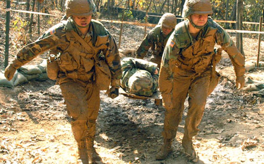 Soldiers emerge from the barbed wire obstacle at Warrior Base, South Korea. The obstacle is one of many that must be negotiated by stretcher teams composed of candidates attempting to qualify for their Expert Field Medical Badges.