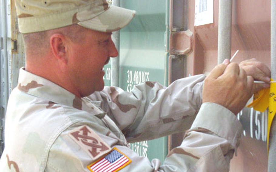 Staff Sgt. Alan Moore, 41, of the Fort Bliss, Texas-based 1836th Transportation Company, affixes a gold tag to a cargo container at Camp Arifjan, Kuwait. The tag signifies that the semi-trailer-sized container has been counted and inventoried. Moore is a member of one of 14 teams from the 143rd Transportation Command counting all the Army’s containers in the Middle East theater.