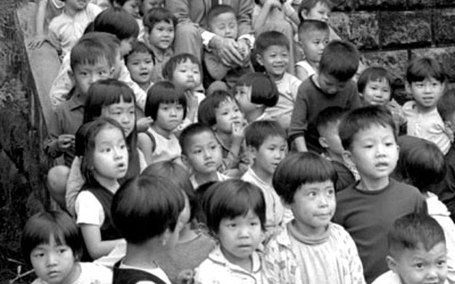 Gregory Peck is surrounded by children as he sits on the steps at Yuan Tung Shih Temple, near Taipei, during filming of ''The Chairman'' in 1968.