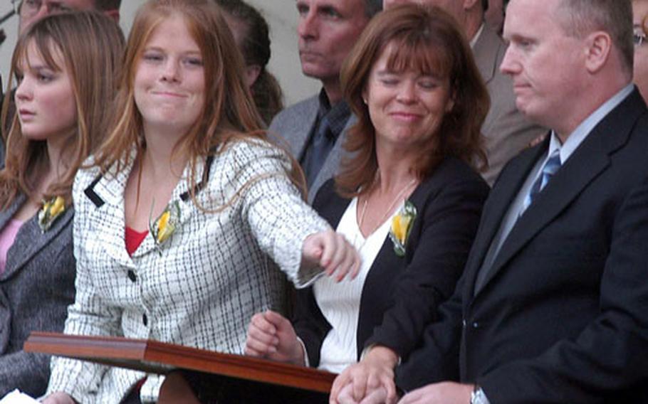 Tessa Pouliot, second from left, reaches past her mother, Carol, to David Caraway during a ceremony at Panzer Casern in Kaiserslautern, Germany, on Friday. Caraway and Tessa’s father, Mike, were awarded the Defense of Freedom Medal. Pouliot was killed and Caraway wounded in a terrorist attack in Kuwait in late January 2003.
