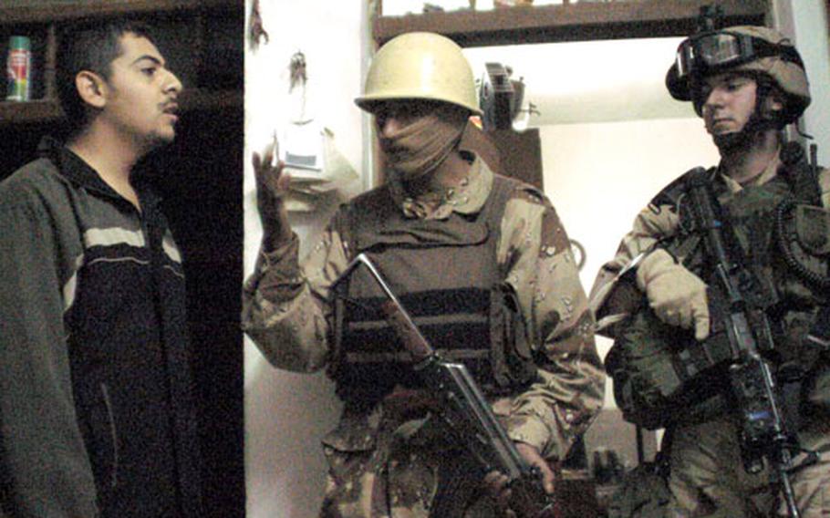 An Iraqi National Guard soldier speaks to a resident in his home during an early-morning mission. The first face a resident sees during a cordon-and-knock mission is always an Iraqi National Guard soldier. Facing insurgents who are increasingly tagerting Iraqi forces, the Iraqi soldiers wear scarves to conceal their identity.