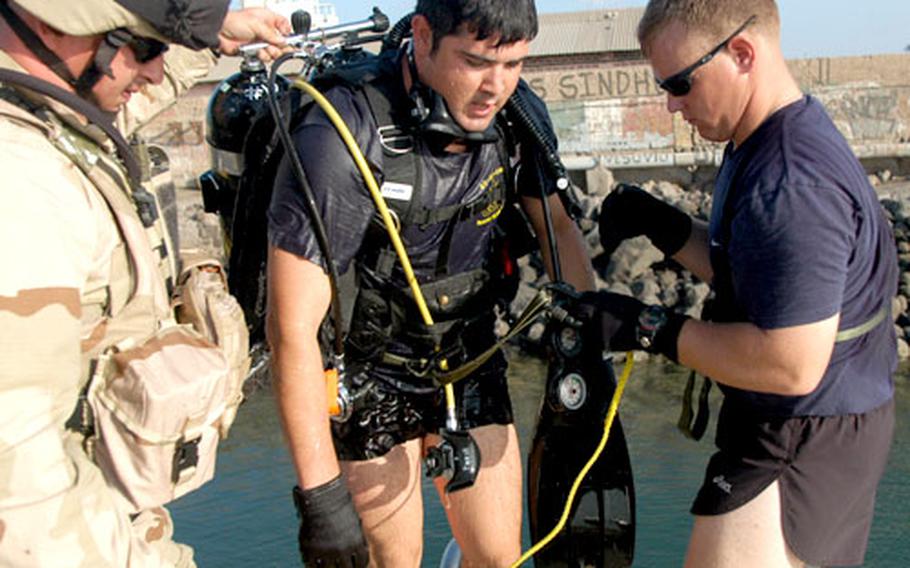 Petty Officer 1st Class Roy Sedano of Chula Vista, Calif., center, climbs out of the water at the Port of Djibouti on Wednesday after inspecting underwater for bombs prior to the arrival of an Army ship.