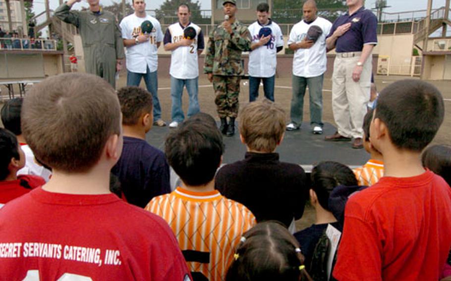 Tech. Sgt. Henry Williams, center, sings the national anthem prior to Saturday’s baseball clinic.
