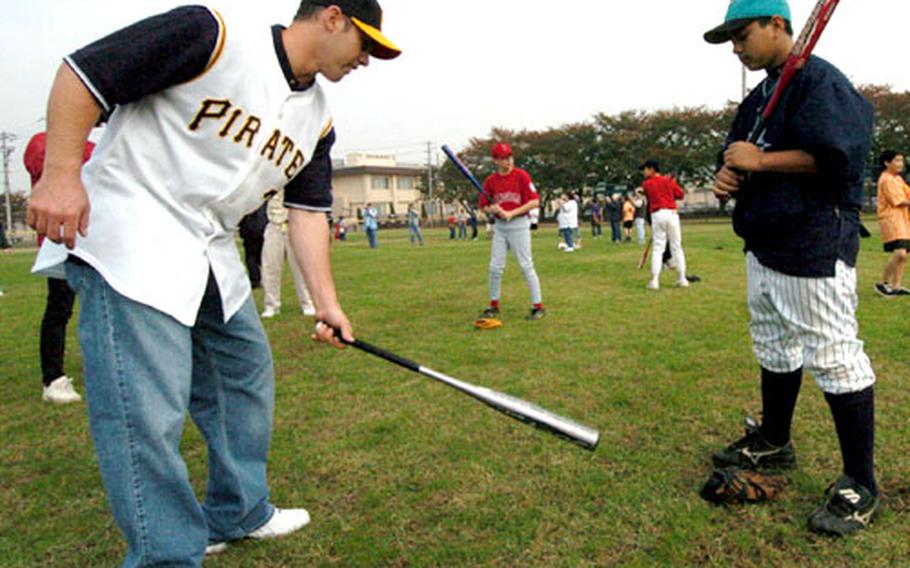 Jack Wilson of the Pittsburgh Pirates, left, gives 12-year-old D.J. "Chainsaw" Roberts batting tips Saturday at Yokota Air Base, Japan.