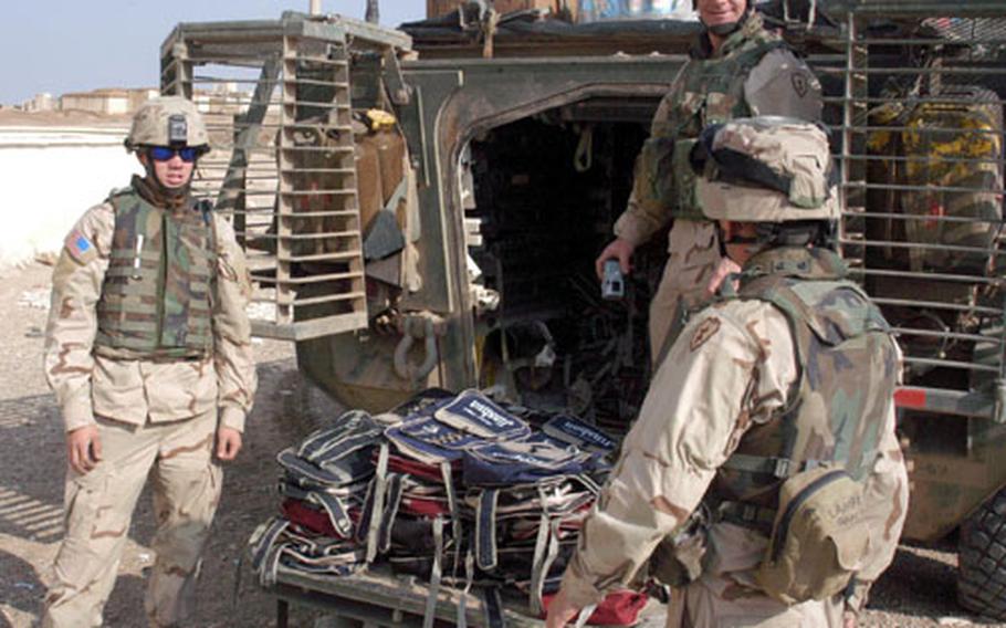 Soldiers with the 14th Cavalry, 1st Brigade, 25th Infantry Division prepare backpacks on the ramp of their Stryker before children rush to collect them.