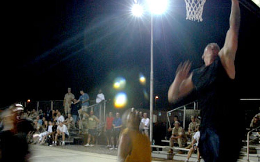 Marine Cpl. Carl Collmer of Prattsburg, N.Y., and the 8th Tank Battalion of Tallahassee, Fla., goes up for a lay-up during a nighttime basketball game at Camp Lemonier, Djibouti. The camp&#39;s 12-team league plays three nights per week.
