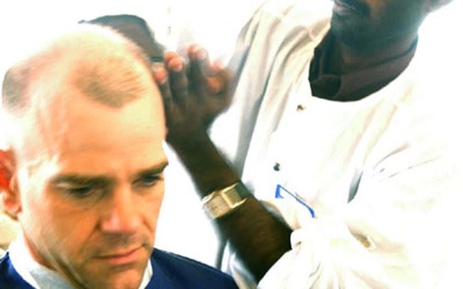 Marine Capt. Scott Johnson of Camp Lejeune, N.C., commandant for Combined Joint Task Force-Horn of Africa at Camp Lemonier, Djibouti, gets a scalp massage from Jiji Lal after his haircut on the base. A haircut, followed by the complimentary scalp massage, costs $5.