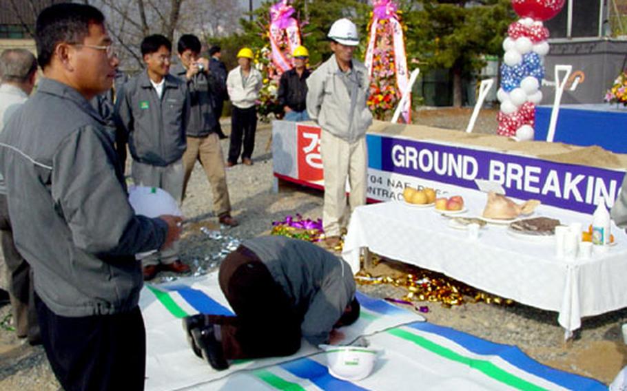 Construction workers bow before a pig’s head, a traditional Korean good luck ceremony, at the groundbreaking of the Camp Carroll Lodge.