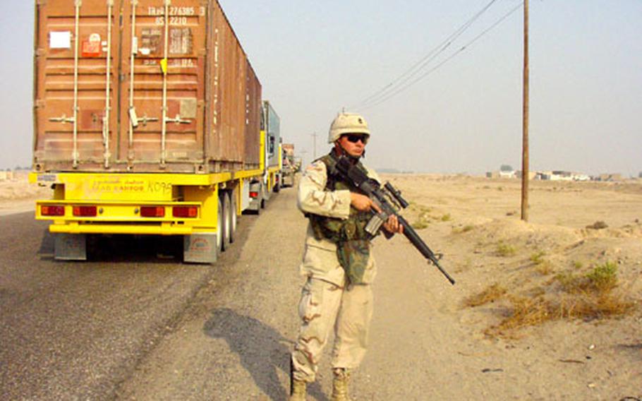 Sgt. 1st Class Joe Litchard, 33, of Roanoke, Va., stands guard over an Iraqi Express truck during a break in the daily Navistar-Anaconda spare-parts convoy.