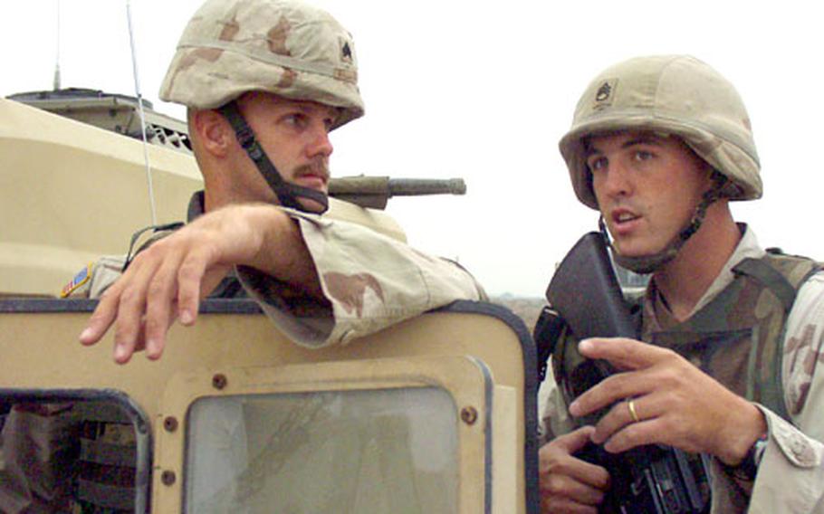 Sgt. Austin “John-o” Williams, left, of the 518th Gun Truck Company, consults with the commander of the Iraqi Express, Staff Sgt. Dan Miller, during a stop in southern Iraq. The Iraqi Express is a daily convoy that hauls needed parts along an increasingly dangerous route from the Iraq-Kuwait border to Balad.