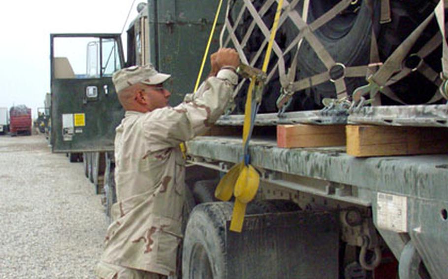 Staff Sgt. David Cardoso, 35, of Dayton, Ohio, secures a load of tires on the back of his flatbed Heavy Equipment Truck at Camp Scania in central Iraq. Cardoso is a truck driver for the 1487th Transportation Company of the Ohio National Guard, one of several units running the daily Iraqi Express spare-parts convoy from Camp Navistar in northern Kuwait to LSA Anaconda, the Army supply hub near Balad, Iraq.