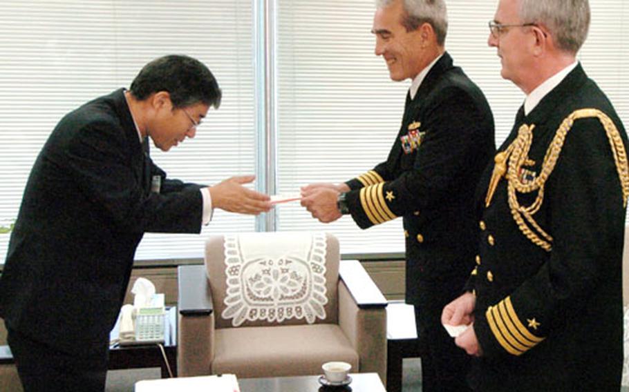 Hideo Minami, director of the Niigata Prefecture Tokyo Office, accepts a donation from Capt. King Dietrich, Commander, Fleet Activities, Yokosuka Naval Base, Japan, during a ceremony Tuesday morning in Tokyo. On the right is Capt. Mark. S. Welch, Defense and Naval Attaché at the U.S. Embassy in Tokyo.