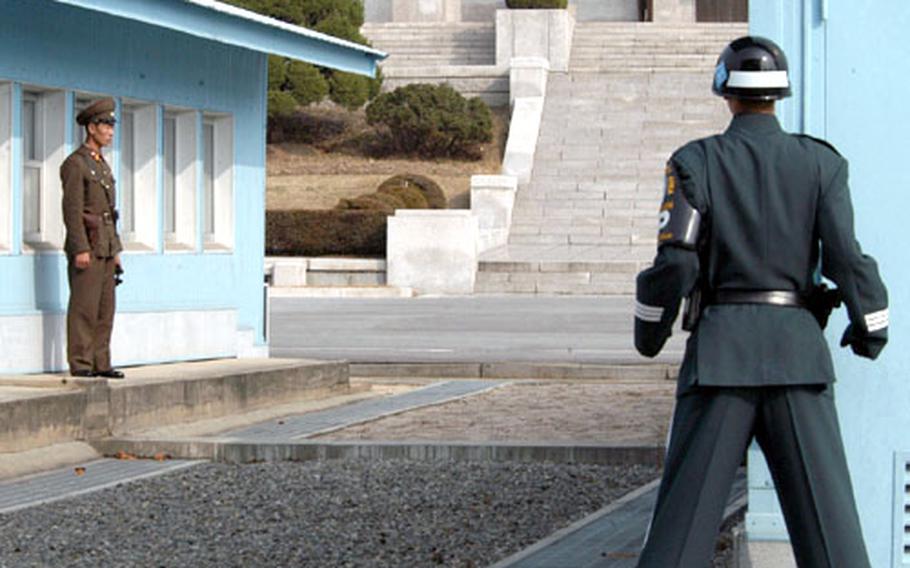 A North Korean military guard, left, and a South Korean guard monitor the Joint Security Area in Panmunjom. Neither guard may speak to the other, nor may they step over the raised curb near the North Korean&#39;s feet, a curb that marks the boundary between the two countries.