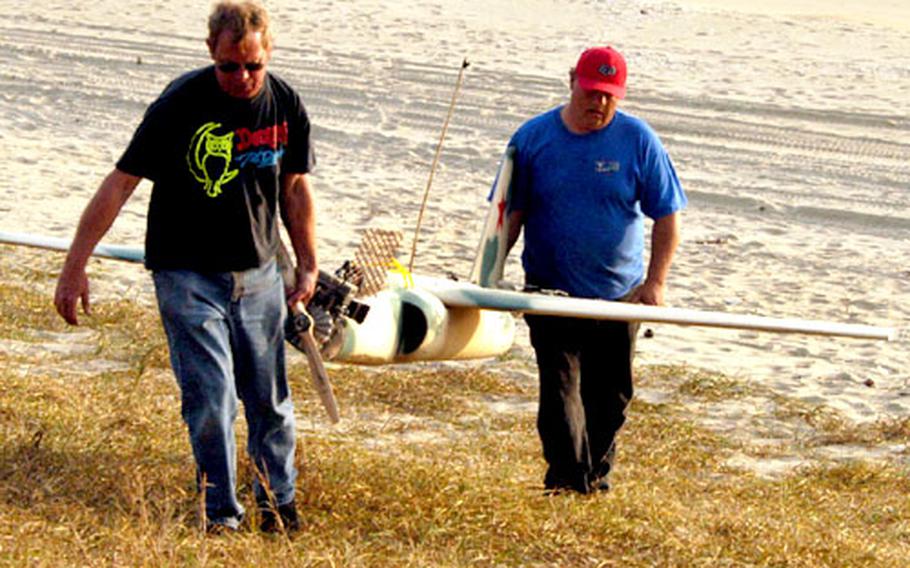 Griffon model aircraft pilots Dan Spinks, left, and Mike Grimm carry a target model from the beach during Sea Strike.