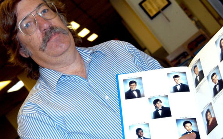Charles Woodruff, Seoul American librarian, holds a yearbook with pictures of Sean Sims, an infantry captain killed Saturday in Iraq.