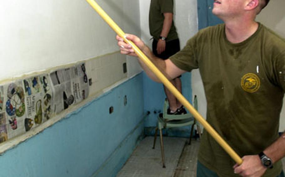 Lance Cpls. John Correll, foreground, and Ryan Davis — both crash, fire and rescue crewmen from Marine Wing Support Squadron 172 — paint the kitchen in the Clark Air Base chapel on Tuesday.