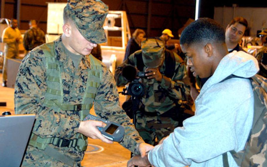 Lance Cpl. Jeff Zeltner, left, cans "noncombatant evacuee" Lance Cpl. Jermaine Reese&#39;s identification number into the Evacuation Control Center NEO tracking system.