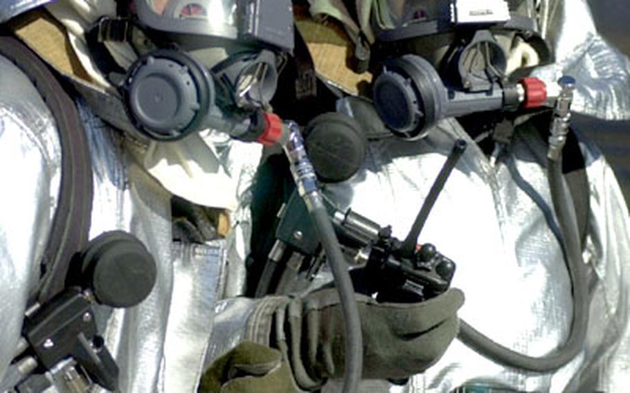 Spanish firefighters at Morón Air Base, Spain, wear protective gear during a space shuttle emergency drill.